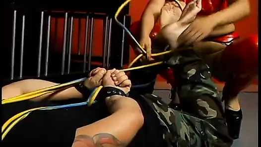 Latex-clad hottie torments a hairy guy with tats