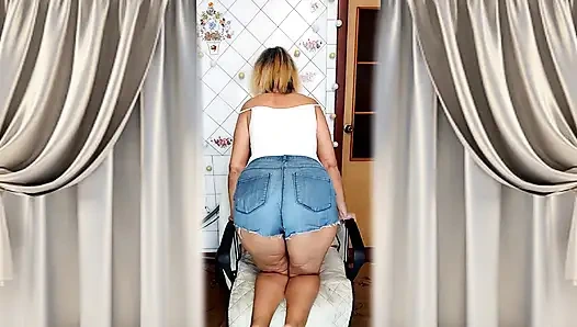 Cheerful housewife Lukerya flirts in the kitchen in tight denim shorts.