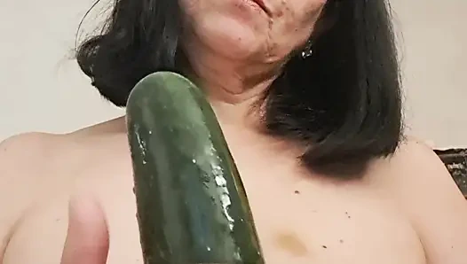 Orta yaşlı seksi kadın göğüsleri ve salatalık ile oynuyor, diliyle ıslatıyor