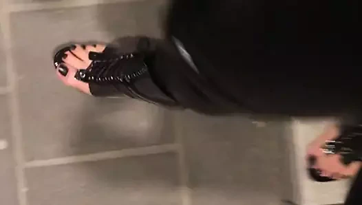 Tren istasyonunda lateks kedi tulumu ve açık topuklu ayakkabılar